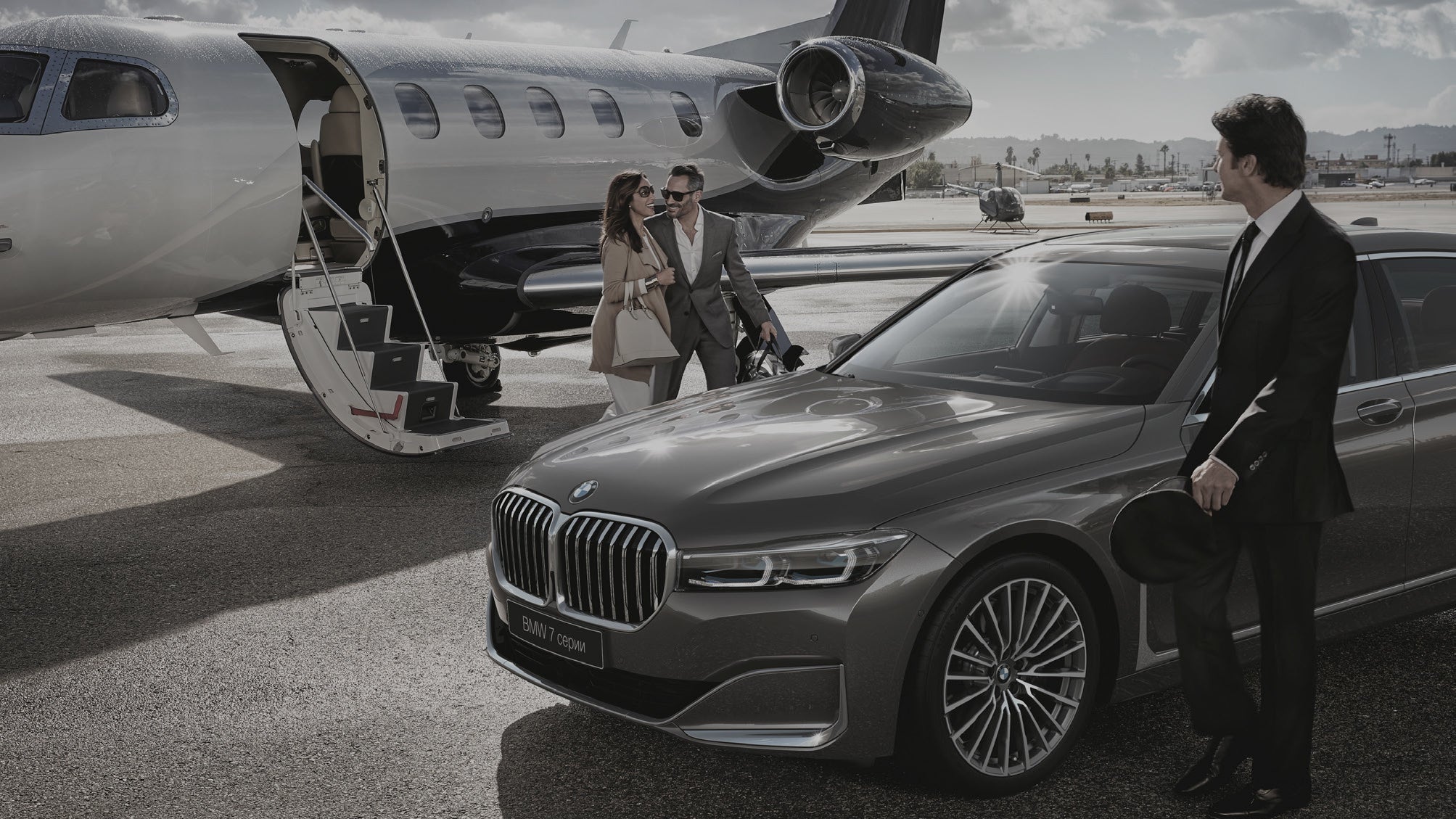 BMW car on a tarmac with a private jet and people in the background