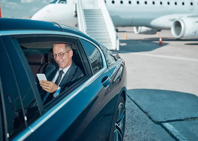 Man in a car at an airport with a plane in the background